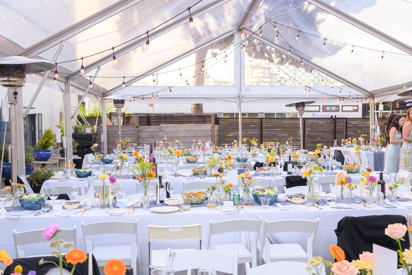 Wedding reception table setup under tent with string lights and wildflower centrepieces